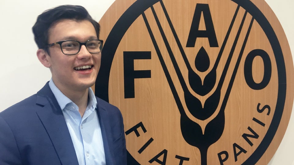orion kobayashi poses in front of FAO sign