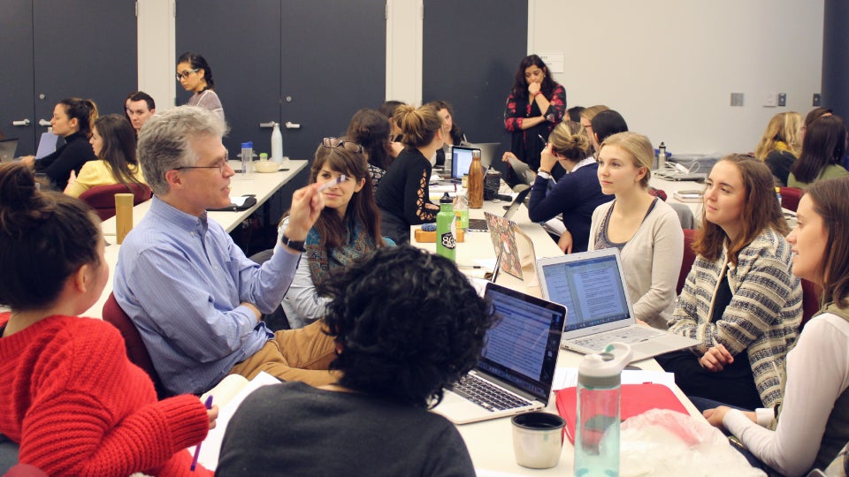 friedman associate professor parke wilde sits at a table with many students discussing ideas to communicate to Orion Kobayashi via Skype